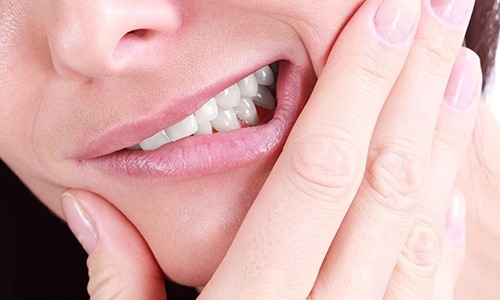 Closeup of person holding mouth in pain