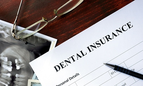 a blank dental insurance form with a pen sitting on top of it