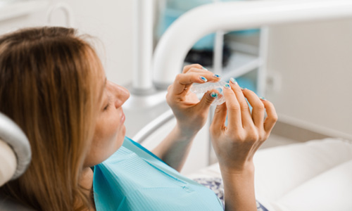 Patient holding clear aligner in treatment room