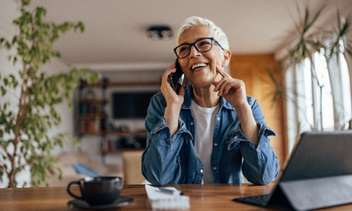 Woman with black glasses smiling while talking on phone