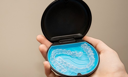 Patient holding clear aligners in black and blue case