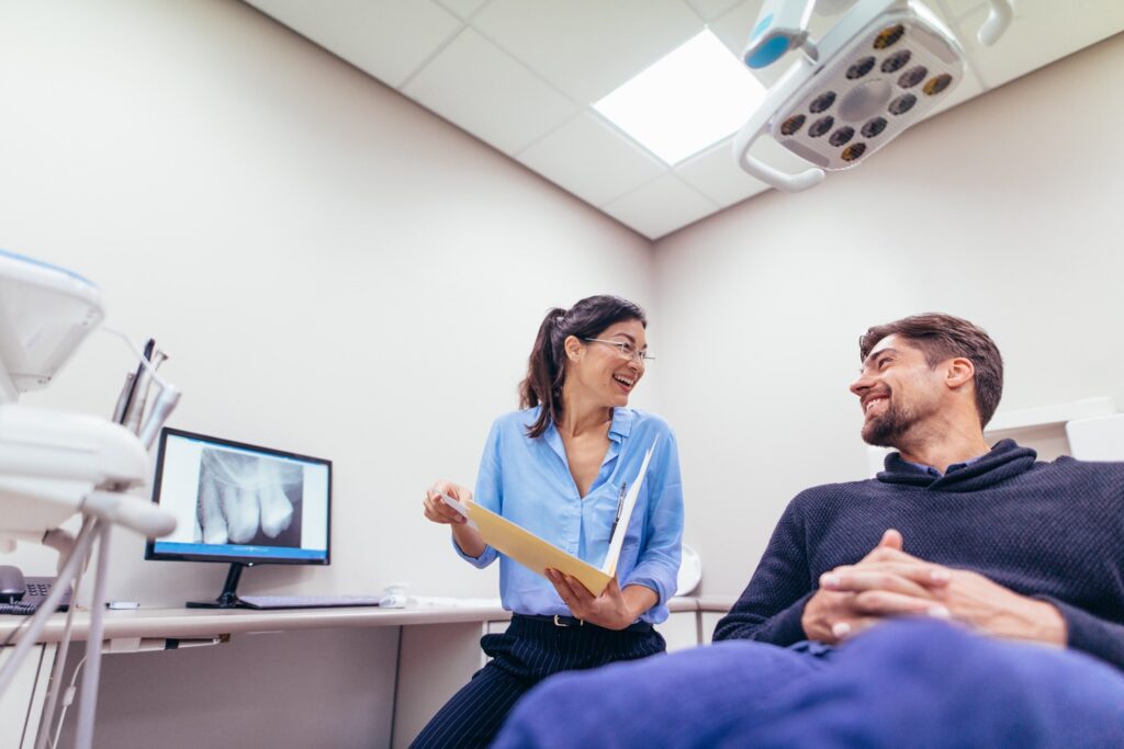 Dentist and patient smiling during dental exam